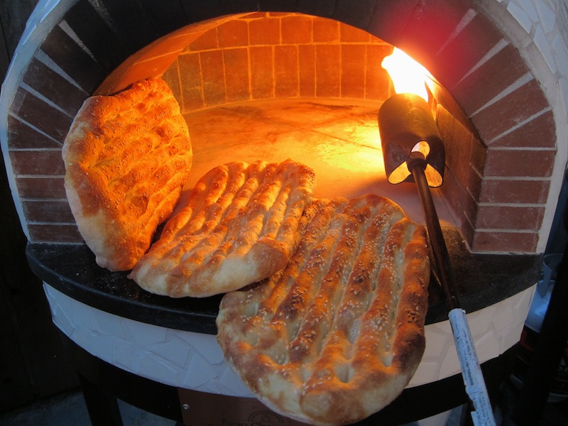 Barbari breads in the process of baking inside the brick oven