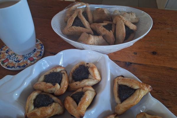 Plates of hamantaschen. Thicker looking gluten-free ones at the back and smaller yeasted ones in front