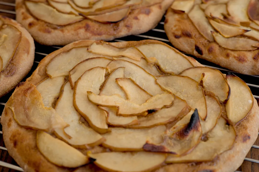 Close up of pear pizza on a cooling rack.